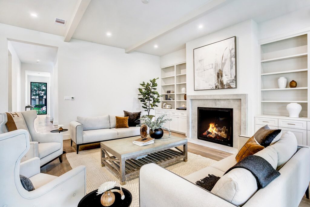 A living room with white furniture and fireplace.